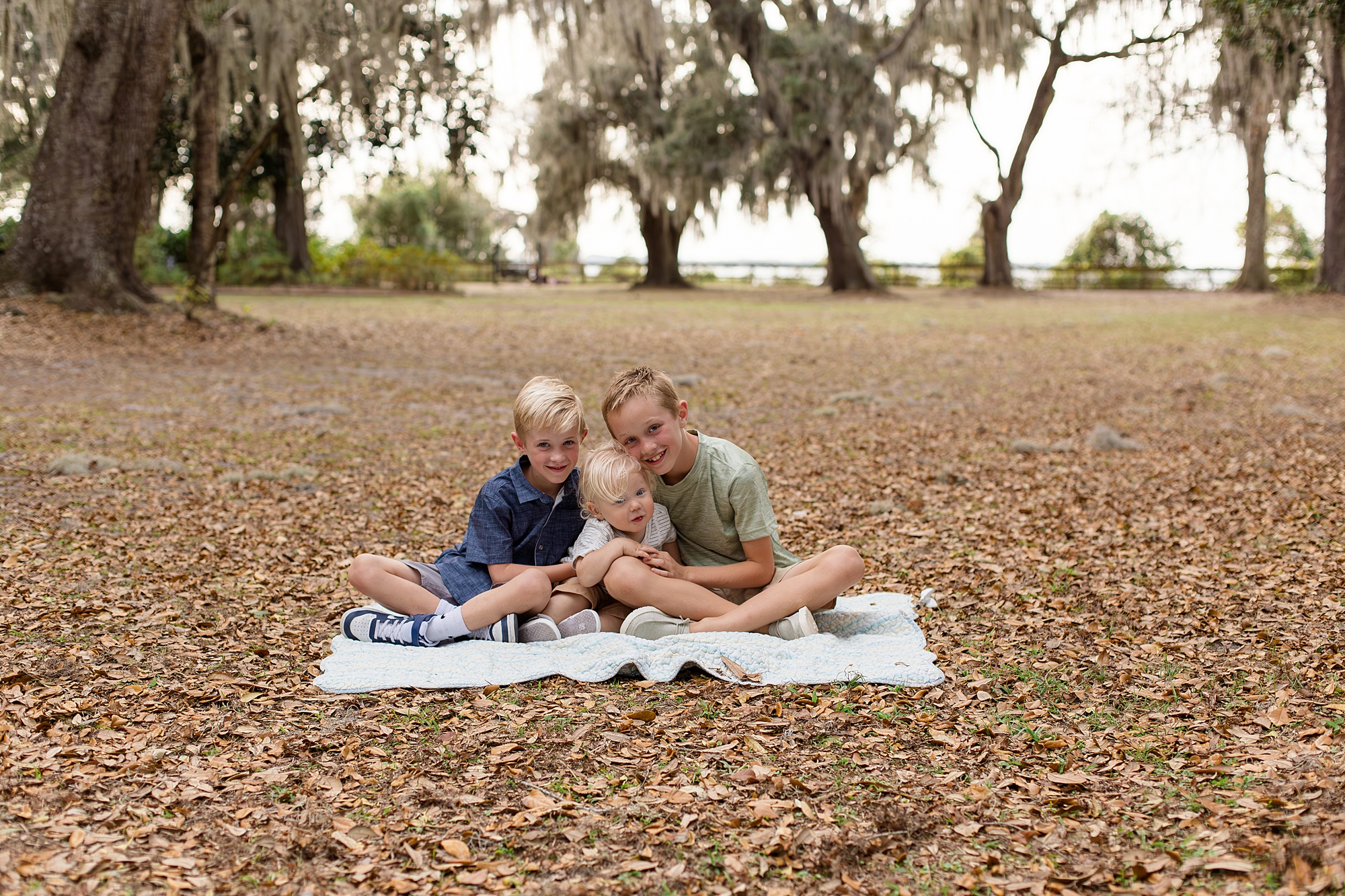 3 little boys sit on blanket in grass at Alpine Groves Park with Jacksonville family photographer, Wisp + Willow Photography Co. 