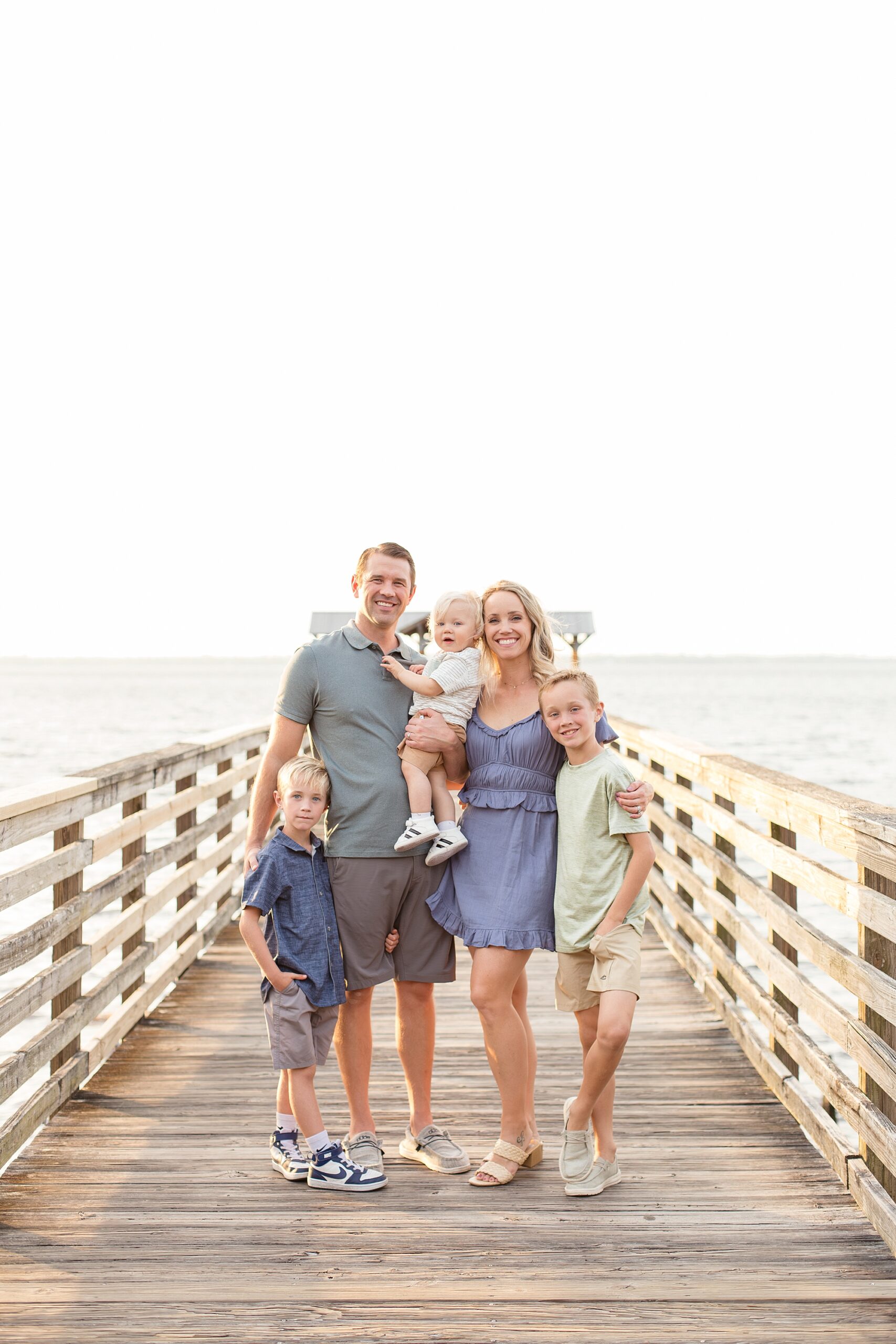 Family of 5 in blue in green stand on pier at Alpine Groves park in Jacksonville, FL with family photographer Wisp + Willow Photography Co.