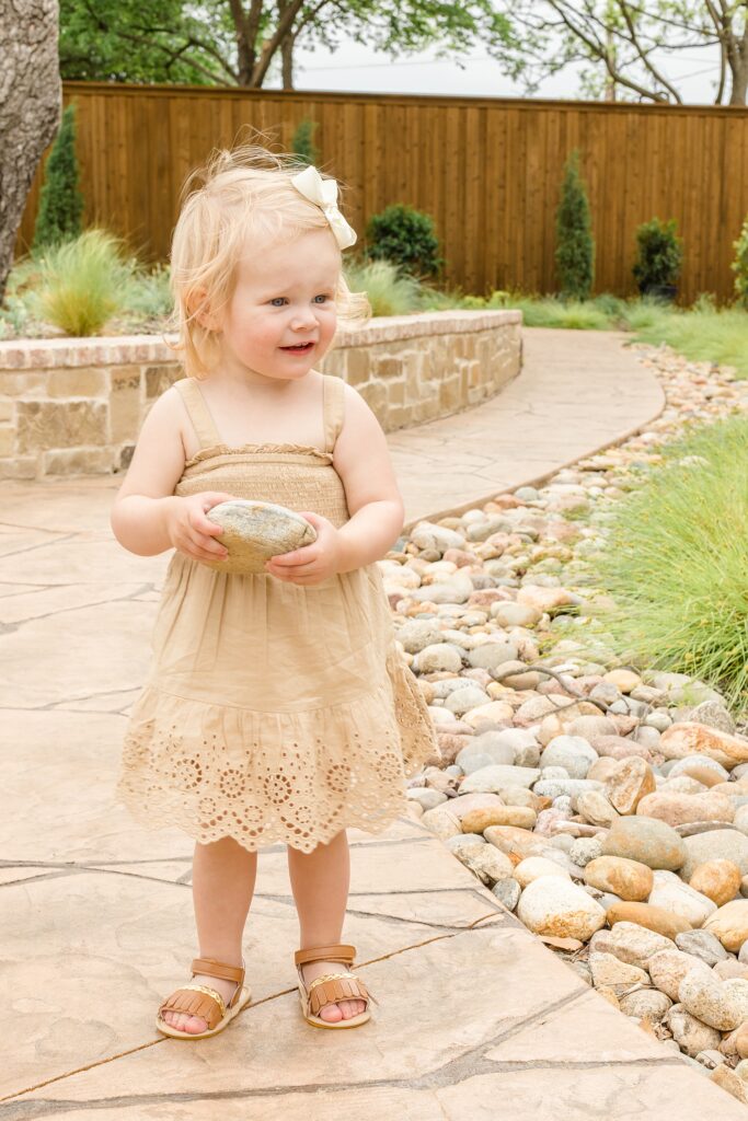 Little girl in tan dress holds rock during spring minis with McKinney family photographer Wisp + Willow Photography Co. 